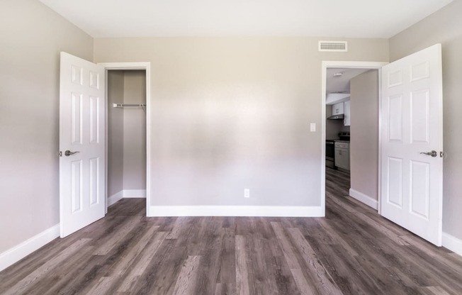 an empty living room with wood floors and white doors