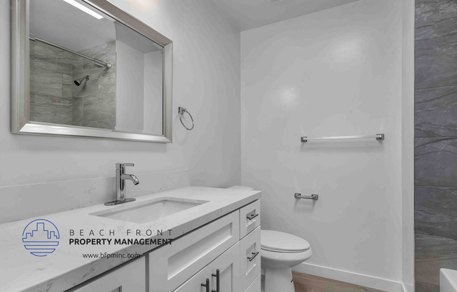 a bathroom with a white sink and toilet and a shower with a glass door