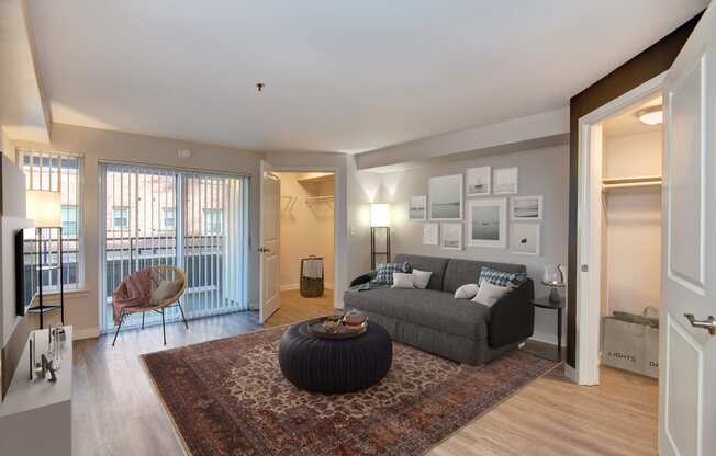 Seattle, WA Luxury Apartments - Union Bay- Living Room with Grey Couch, Patio Entrance, and Circle Coffee Table