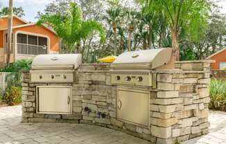 an outdoor kitchen with two grills and two stoves