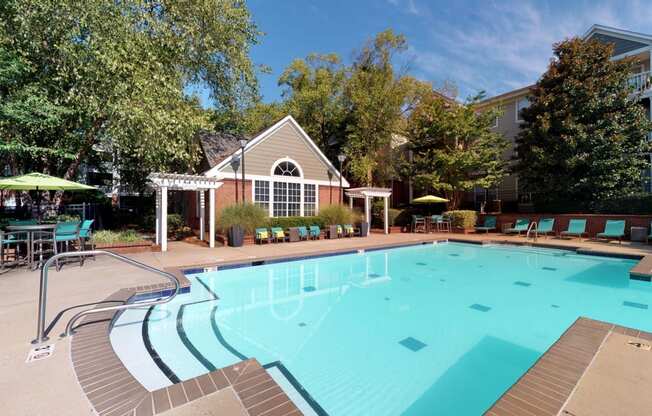 a swimming pool with lounge chairs and umbrellas in front of a building