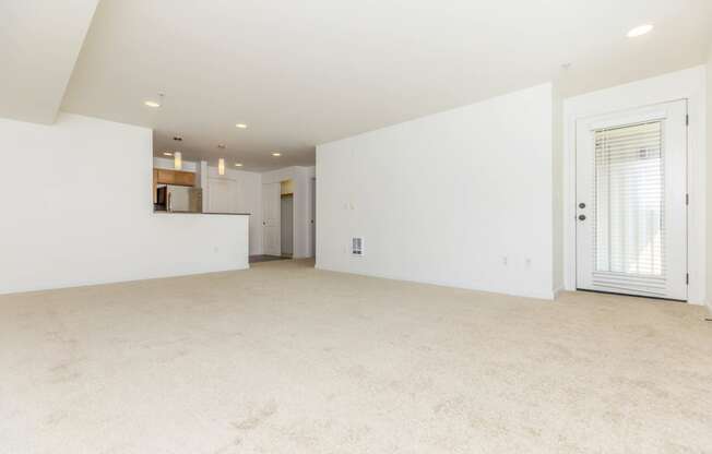 the living room and kitchen of an empty home with white walls and carpet  at Delano, Redmond, 98052