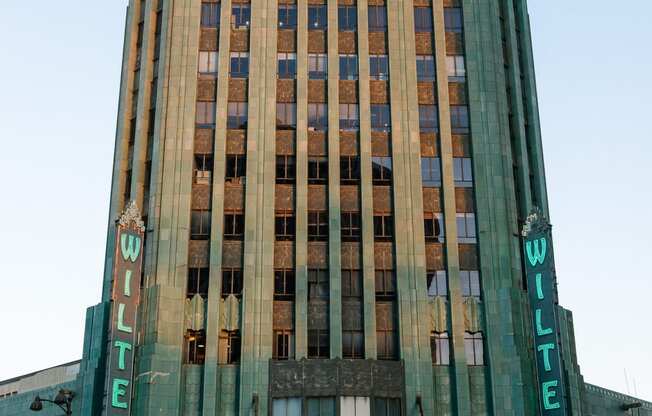 a tall brown and green building with a blue sky in the background