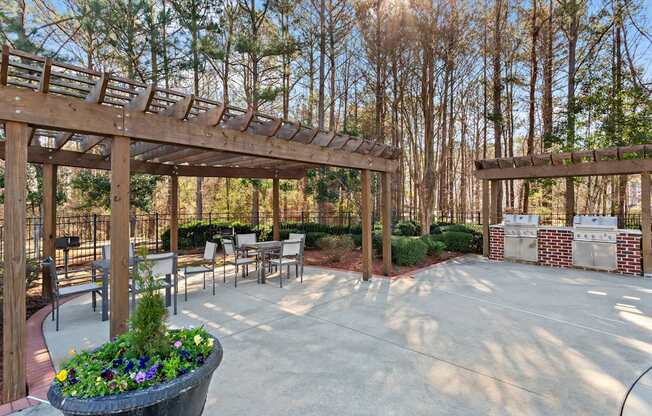 A patio with a wooden pergola and a planter with purple flowers.