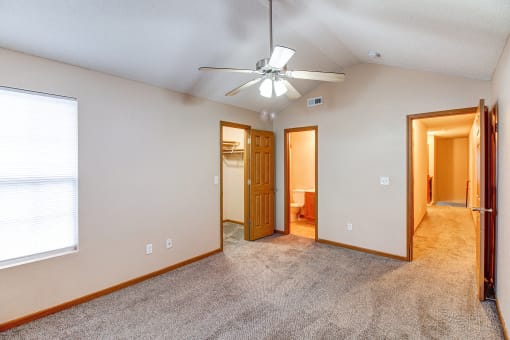 an empty living room with a ceiling fan and a window