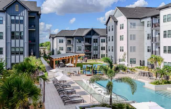 A pool area with a slide and sun loungers in front of apartment buildings.