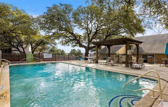 A large swimming pool surrounded by trees and lounge chairs.