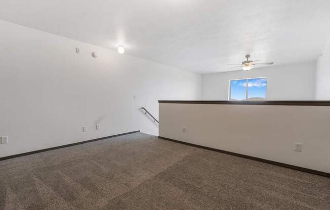 A room with a carpeted floor and a window with a view of the sky.