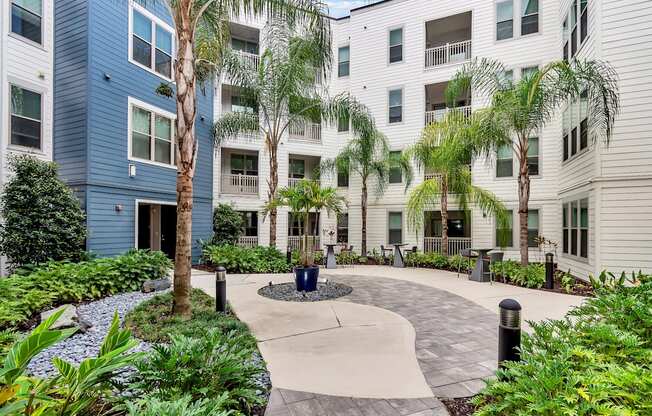 a circular walkway with trees and plants in front of an apartment building