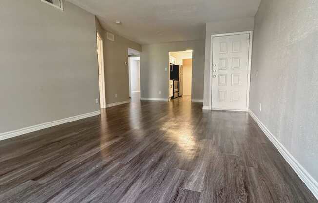 an empty living room and dining room with wood flooring