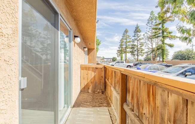 the balcony has a wood railing and a glass door