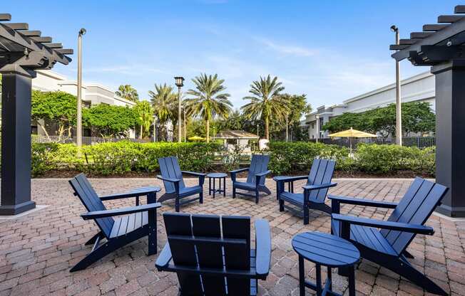 a patio with blue chairs and umbrellas on a brick sidewalk