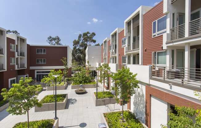 a courtyard with trees and plants in front of an apartment building