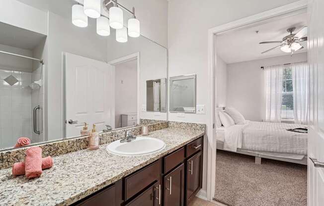 A bathroom with a sink, mirror, and bed.