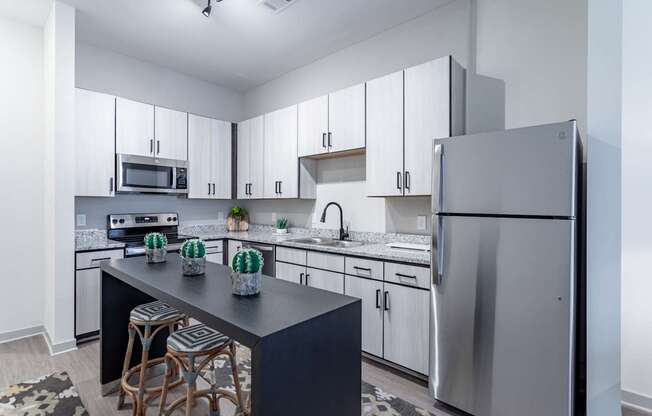 A modern kitchen with a black countertop and stools.
