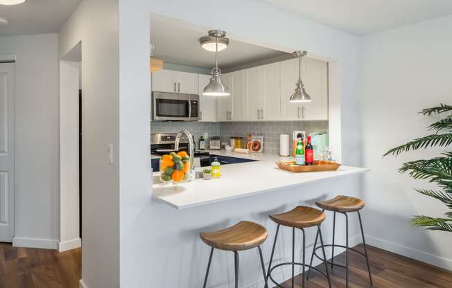 a kitchen with a white counter top and three stools