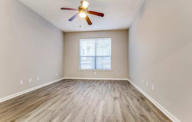 an empty living room with hardwood floors and a ceiling fan