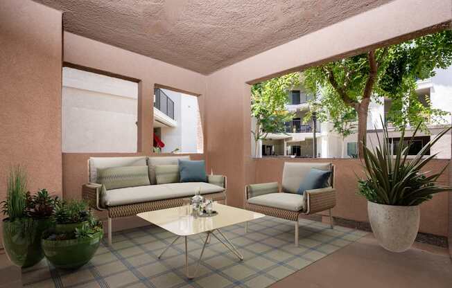A patio area with a couch, chair, and potted plants.