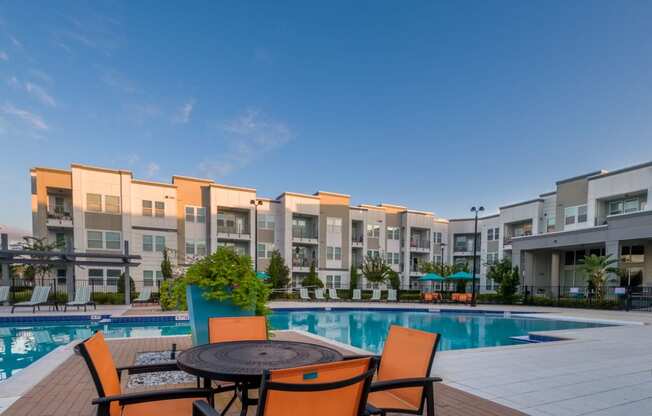 a swimming pool at an apartment complex with orange chairs and a table