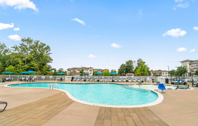 a swimming pool with chairs and umbrellas at the resort on a sunny day