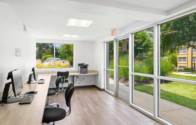 an office with windows and a desk with chairs and a computer