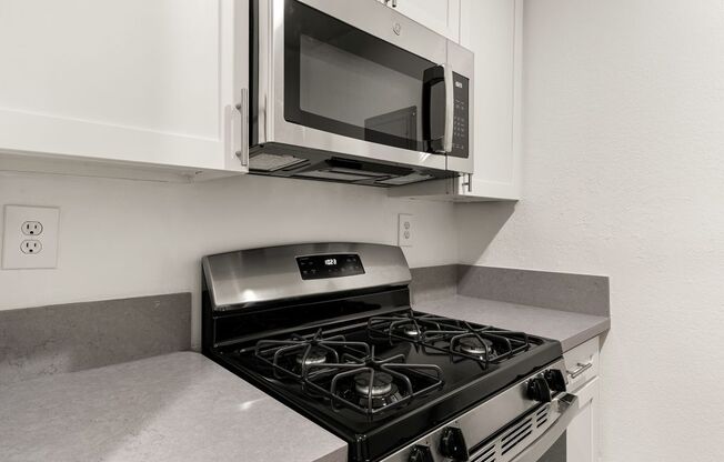 A modern kitchen with a black stove and a microwave above it.