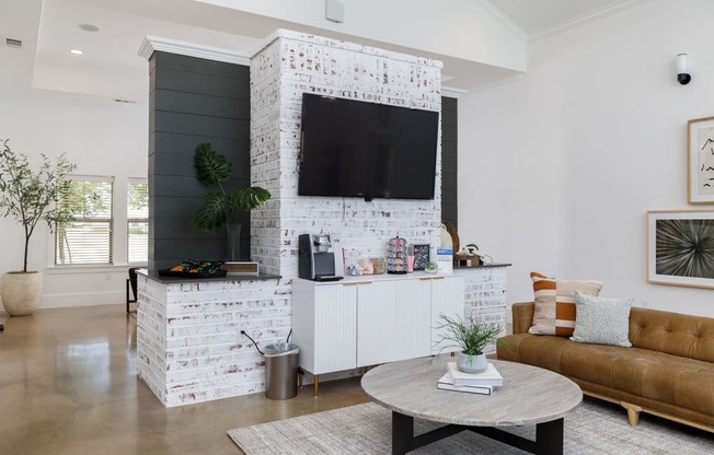 a living room with a white brick accent wall and a large flat screen tv on top of