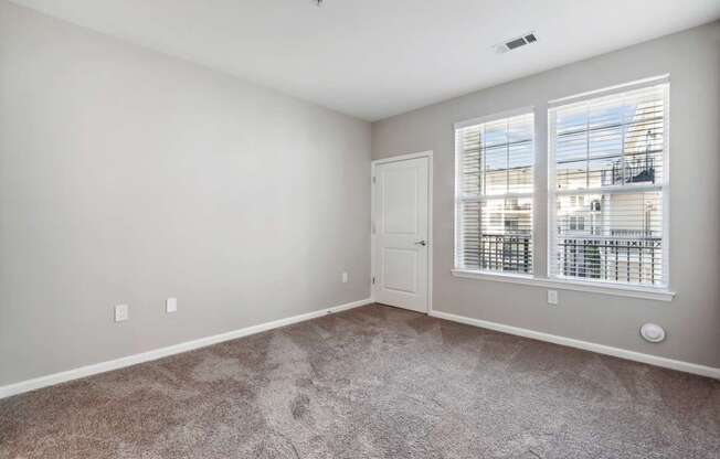 A room with a carpeted floor and a window with blinds.