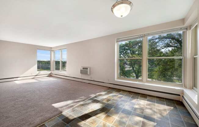 an empty living room with large windows and a rug