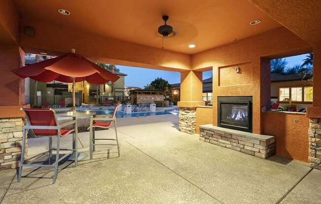 A patio with a fireplace and chairs.