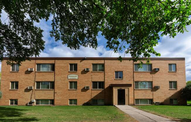 a brick building with a sidewalk and a tree. Fargo, ND Morningside Apartments