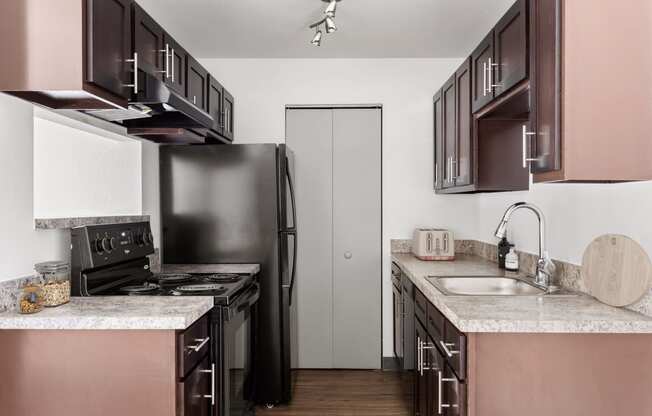 a kitchen with black appliances and white counter tops and brown cabinets at Verona, Littleton, CO, 80123