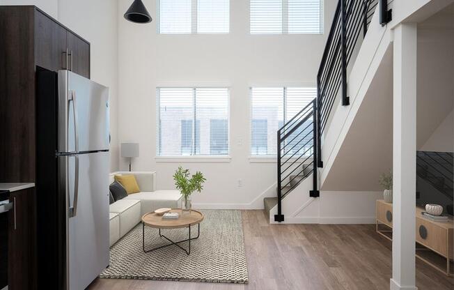 a living room with a refrigerator and a staircase