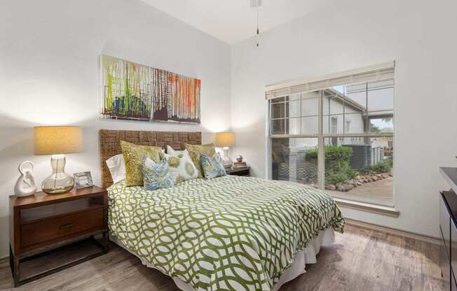 A bedroom with a bed, nightstand, and a painting on the wall.