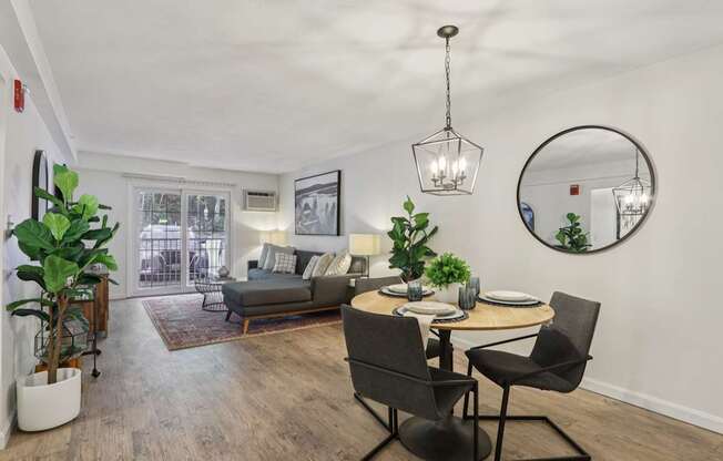 A modern dining room with a round mirror and a table set for two.