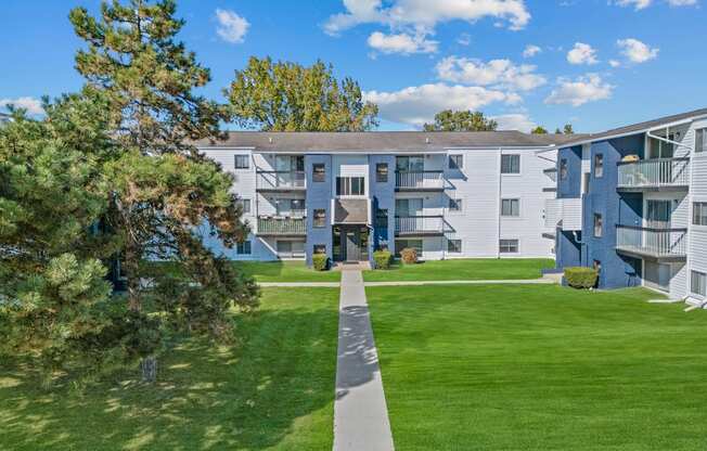 the view of an apartment building with a green lawn and trees