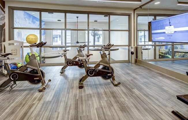 a gym with exercise bikes and a tv on the wall at Arise Riverside, Austin, TX