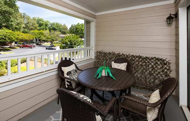A patio with a table and chairs overlooking a parking lot.