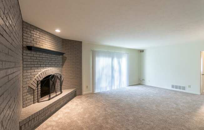 This is a photo the living room with brick wall and wood-burning fireplace of the 925 square foot, Hazelnut 2 bedroom, 1 bath apartment at Montana Valley Apartments in the Westwood neighborhood of Cincinnati, OH.