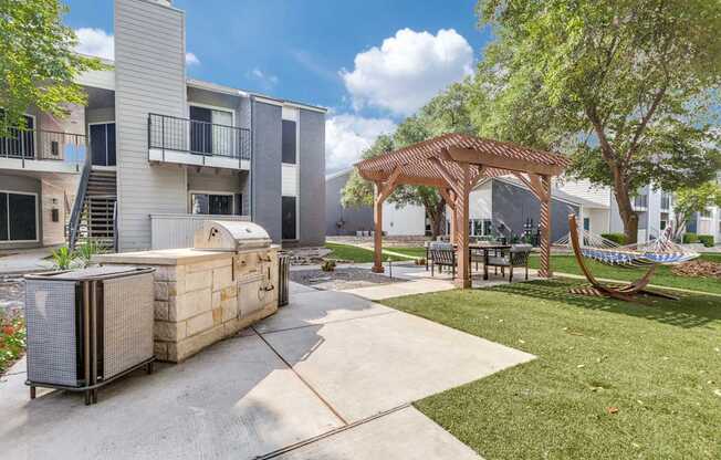 A patio area with a grill and seating area in front of apartment buildings.
