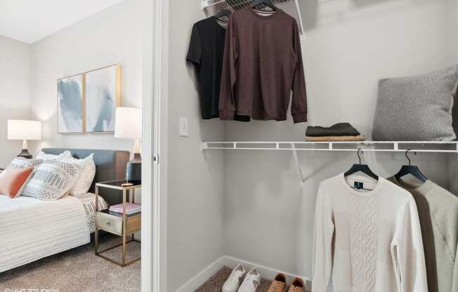 a bedroom with a closet with clothes on a rack and a bed