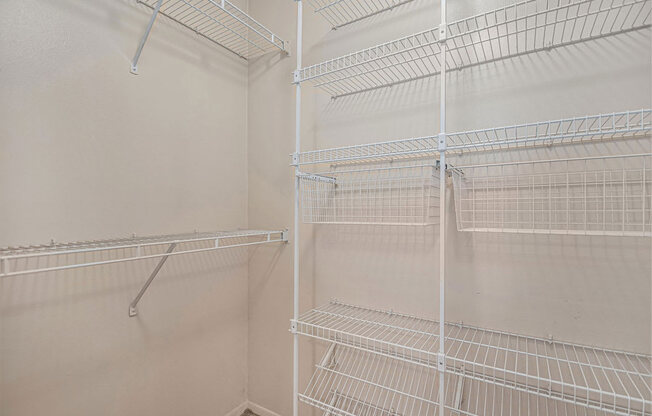 the walk in closet in the master bedroom has white wire shelves