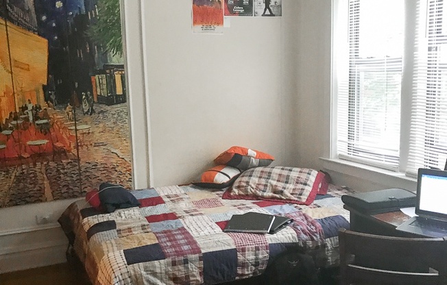 a bedroom with a bed and a desk and a painting on the wall