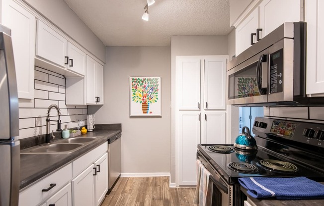 a spacious galley kitchen in Stadium 700 luxury apartments in Arlington TX with stainless steel appliances and white cabinets