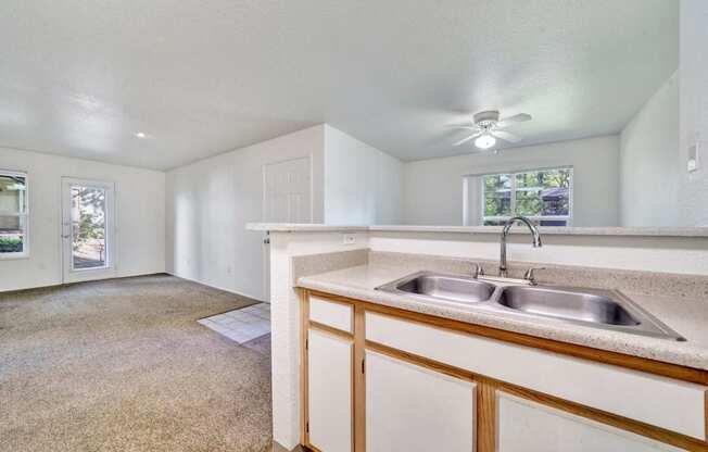 an empty kitchen with a sink and a ceiling fan