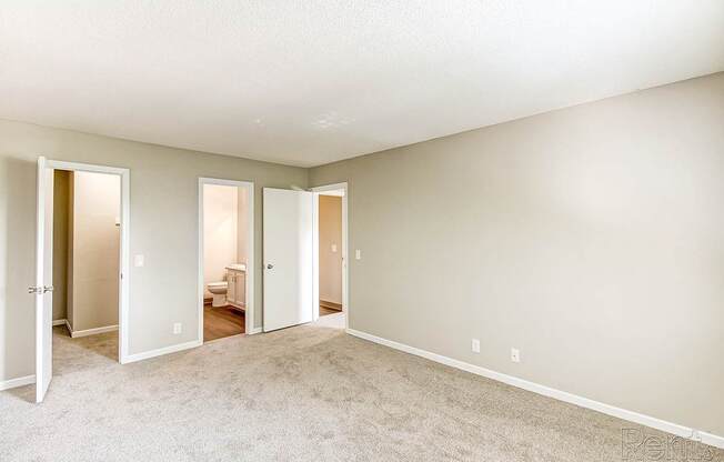 an empty room with a carpeted floor and a door to a bedroom