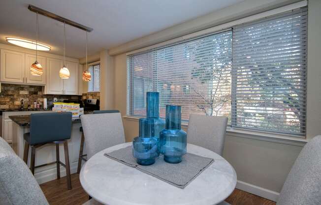 a dining room with a table and chairs and a kitchen in the background