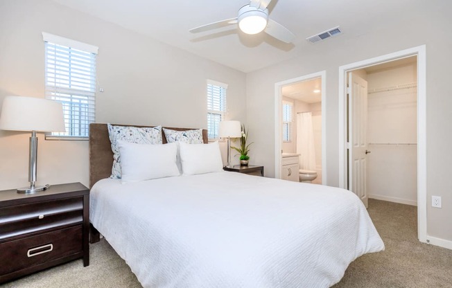 a bedroom with a large white bed and a ceiling fan