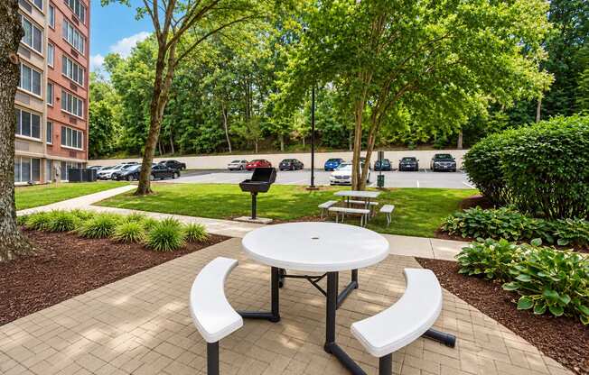 A white picnic table with two benches is in the middle of a brick patio.