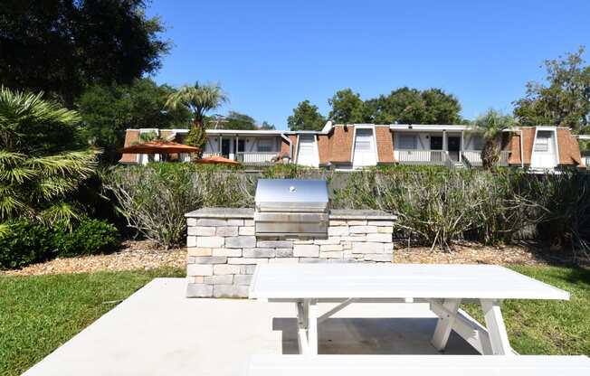 a picnic table and a grill in a yard in front of a house